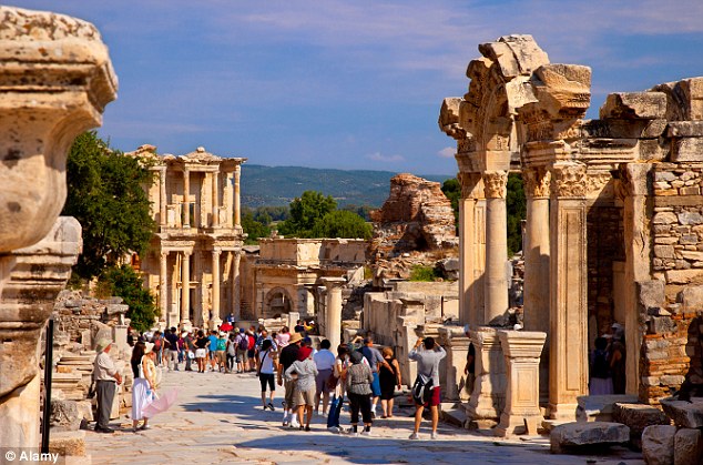 Tourists walk the marble-paved street of Curetes near the Temple of Hadrian and Library of Celsus in Ephesus 
